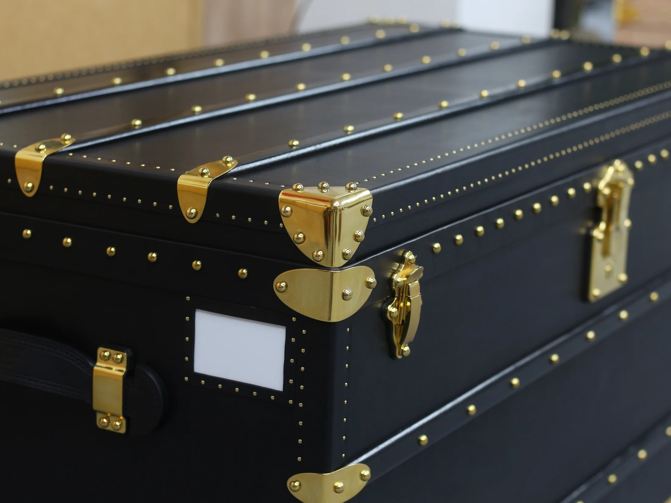 Close view of a black handcrafted trunk with gold-tone fittings