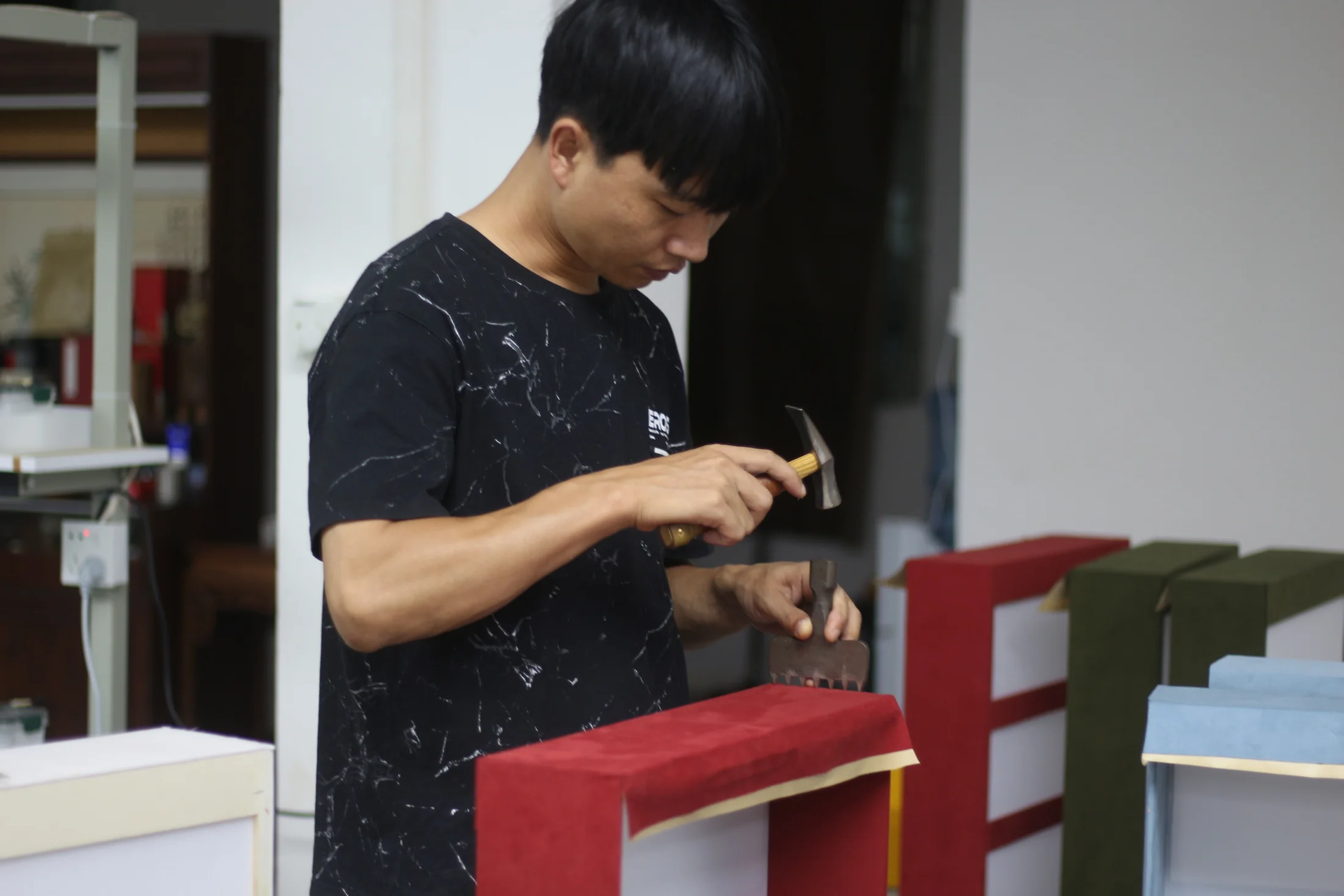 A Pusu Atelier maker hand-finishing a red case at the workbench