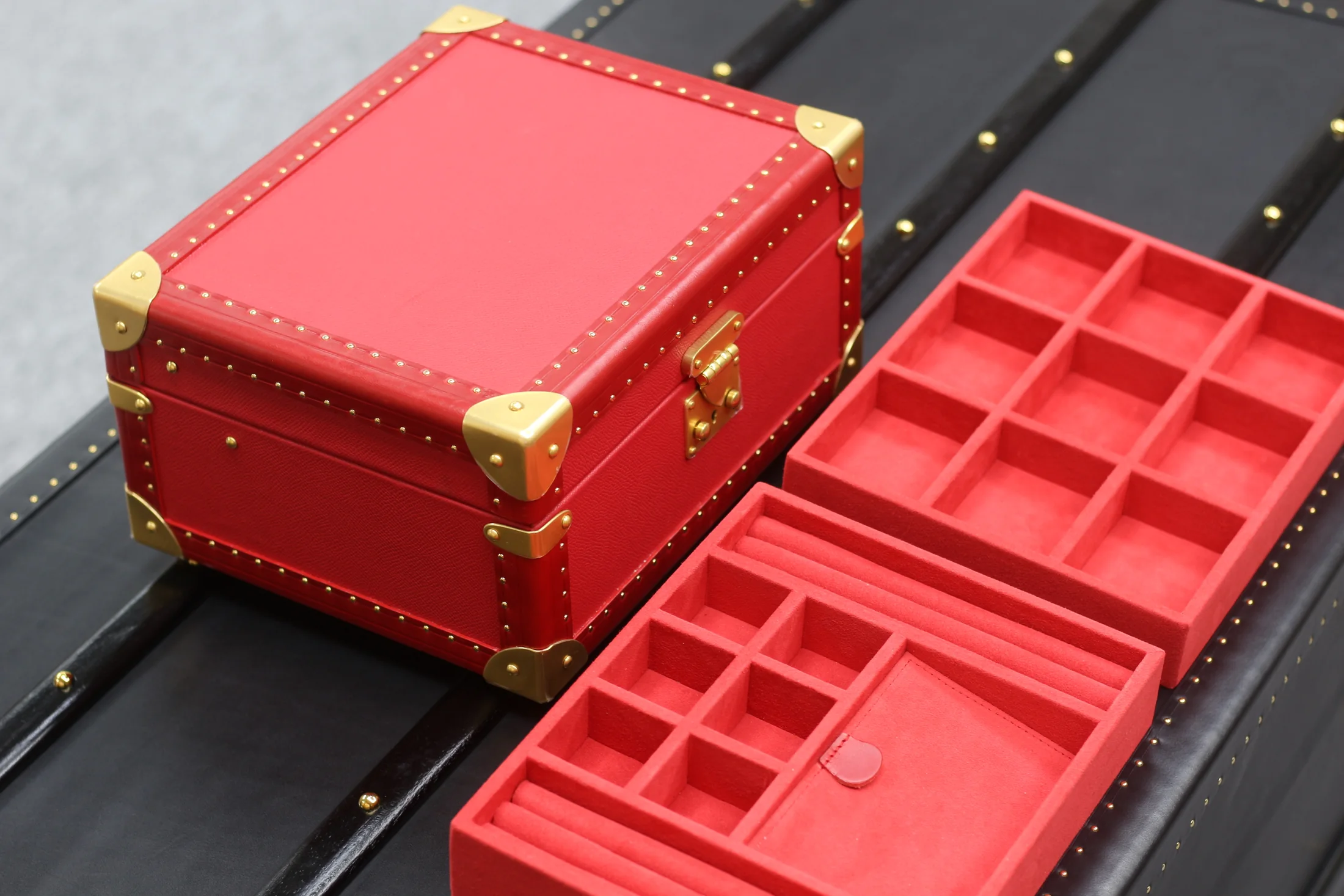 Red handcrafted jewelry case with gold-tone fittings and fitted red storage trays