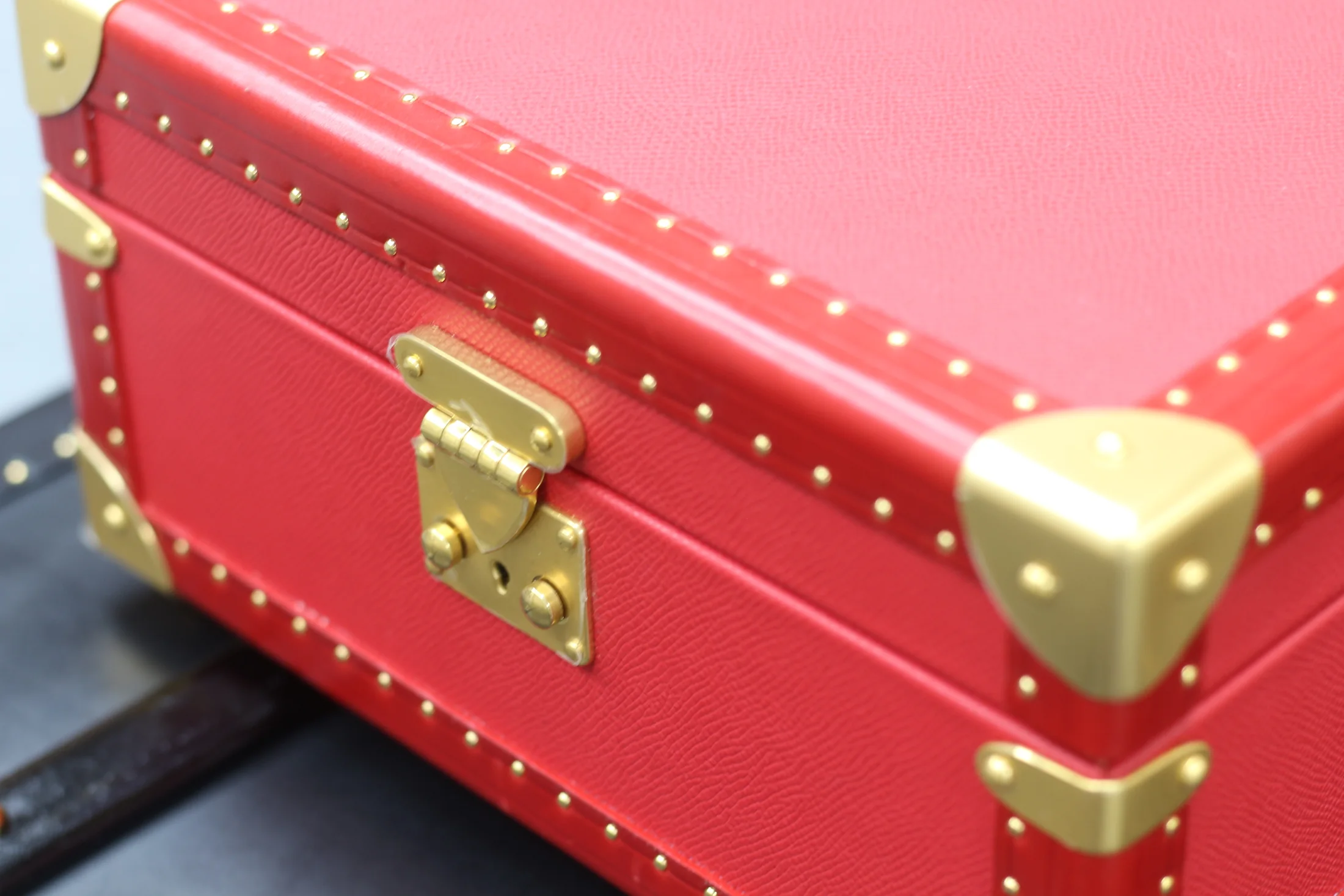 Close view of a red case corner, stitching and gold-tone fitting